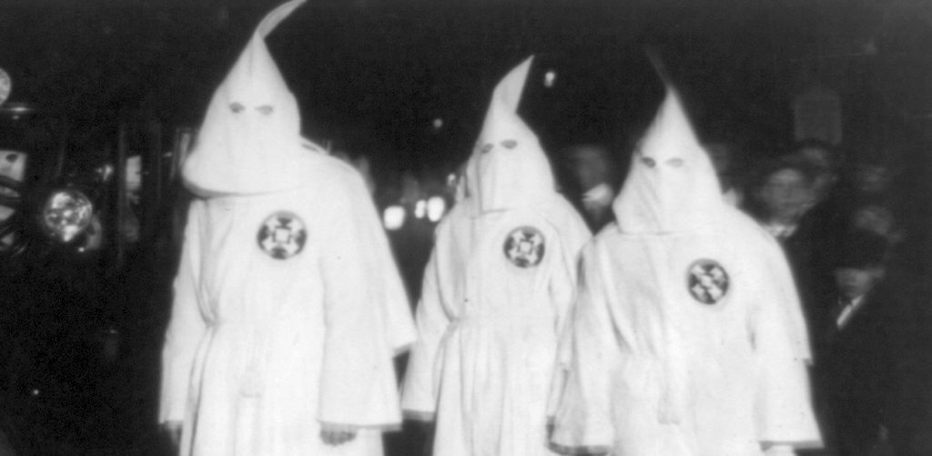 Three Ku Klux Klan members standing beside automobile driven by Klan members at a Ku Klux Klan parade through counties in Northern Virginia bordering on the District of Columbia Library of Congress