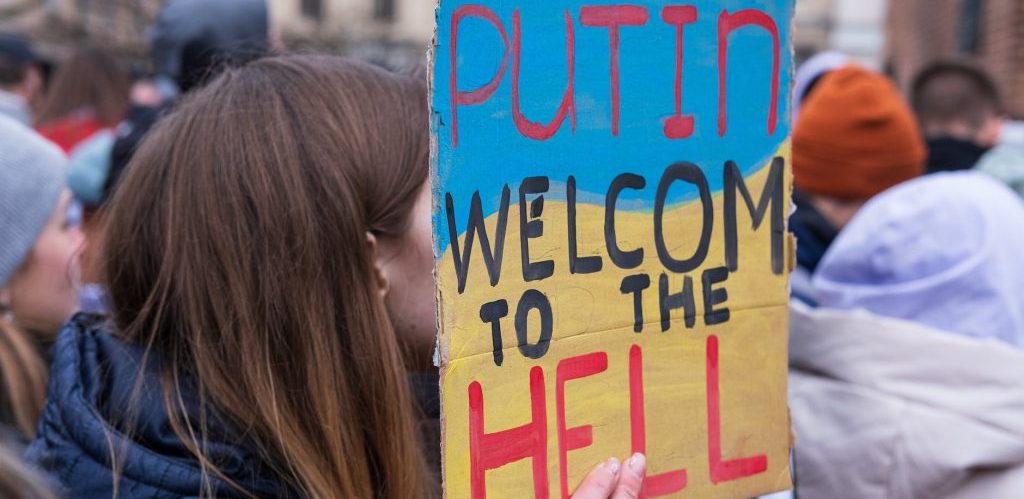 a person holding a placard that says putin welcome to the hell