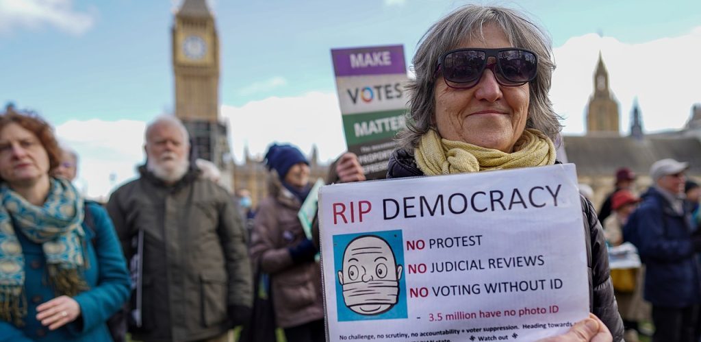 A protester with a placard RIP Democracy during a demonstration against the Elections Bill by Alisdare Hickson