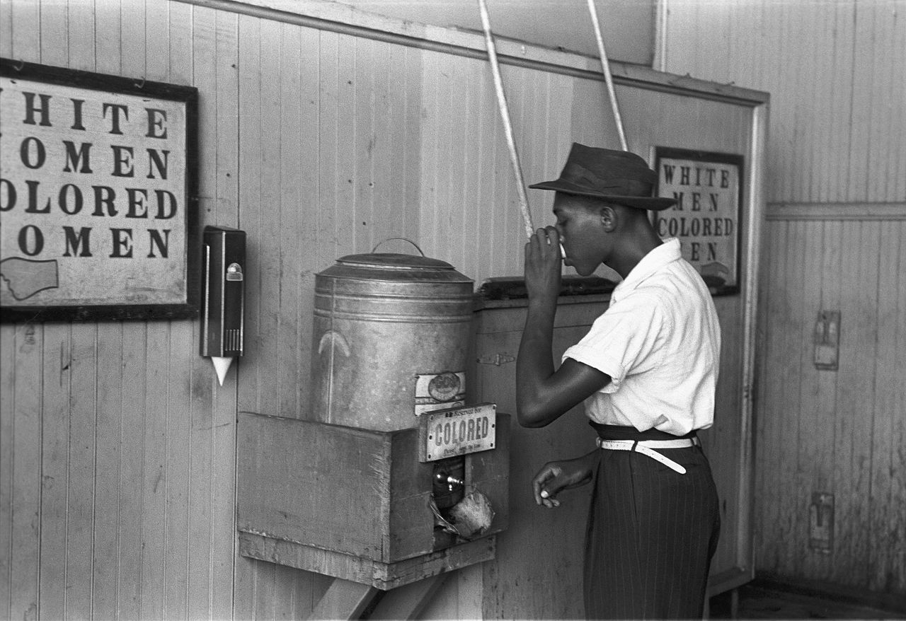 Colored drinking fountain from mid 20th century with African American drinking by Russell Lee