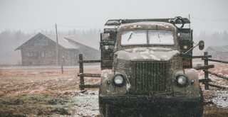 brown and grey vehicle near brown wooden fence during rain