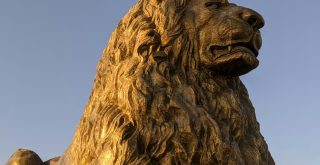 a statue of a lion is shown against a blue sky